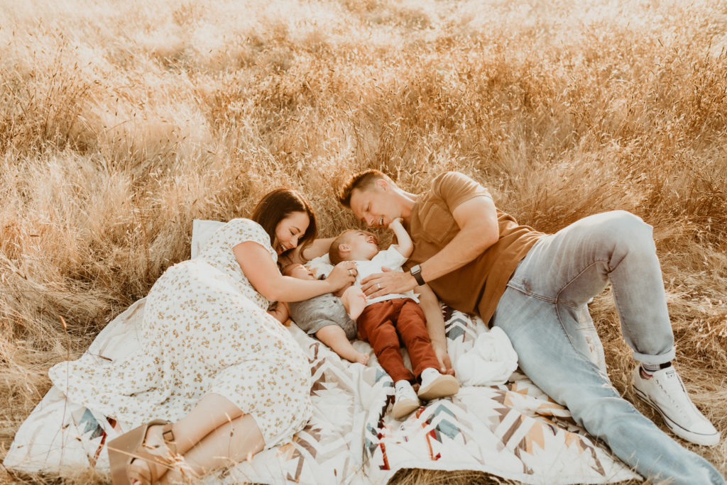 family of four snuggling on a blanket in a field