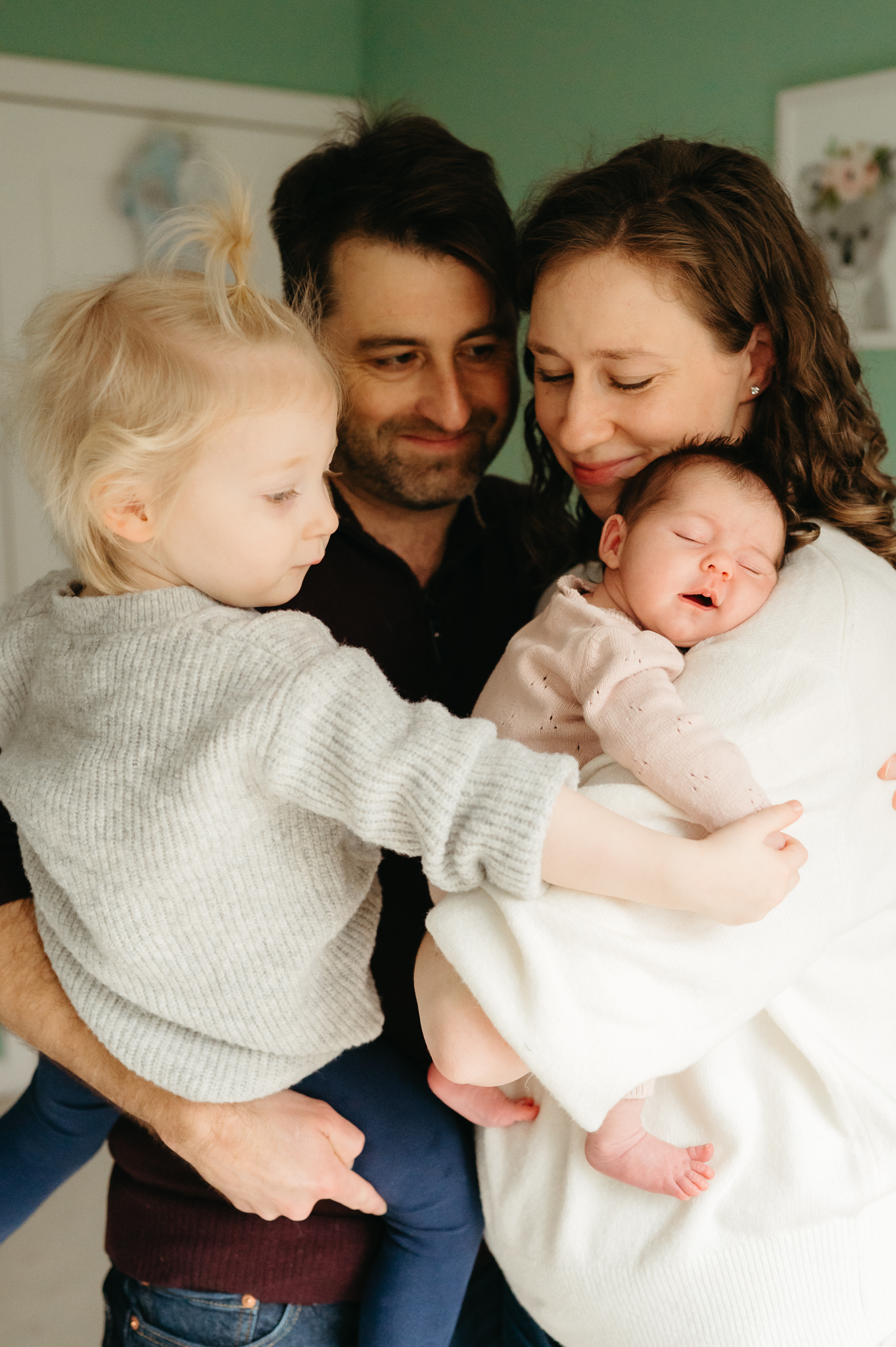 Intimate in-home newborn photography session capturing a tender moment between parents and their baby, emphasizing connection and authenticity.