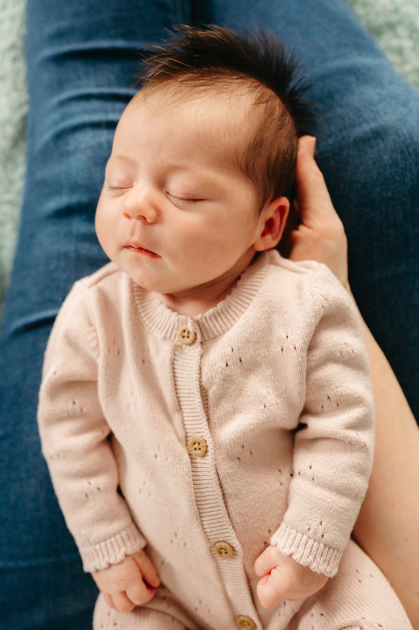 Close-up in-home newborn photography shot of a baby's tiny hands, highlighting precious details in a relaxed and intimate setting