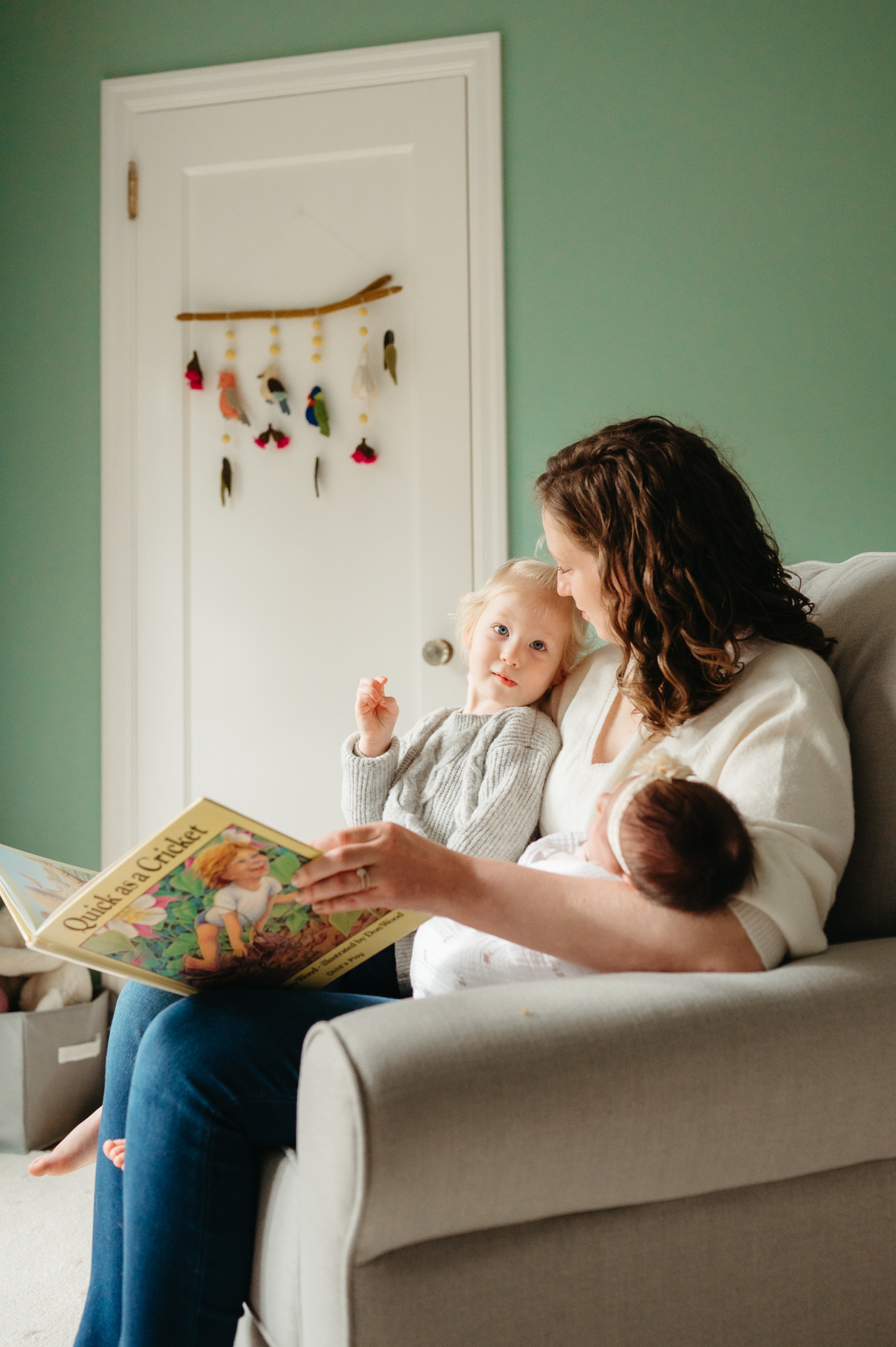 Intimate in-home newborn photography session capturing a tender moment between parents and their baby reading a book, emphasizing connection and authenticity.