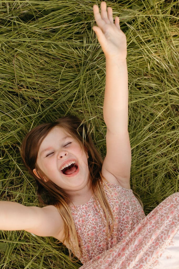 spring family photos in portland oregon featuring a joyful little girl laughing in the grass