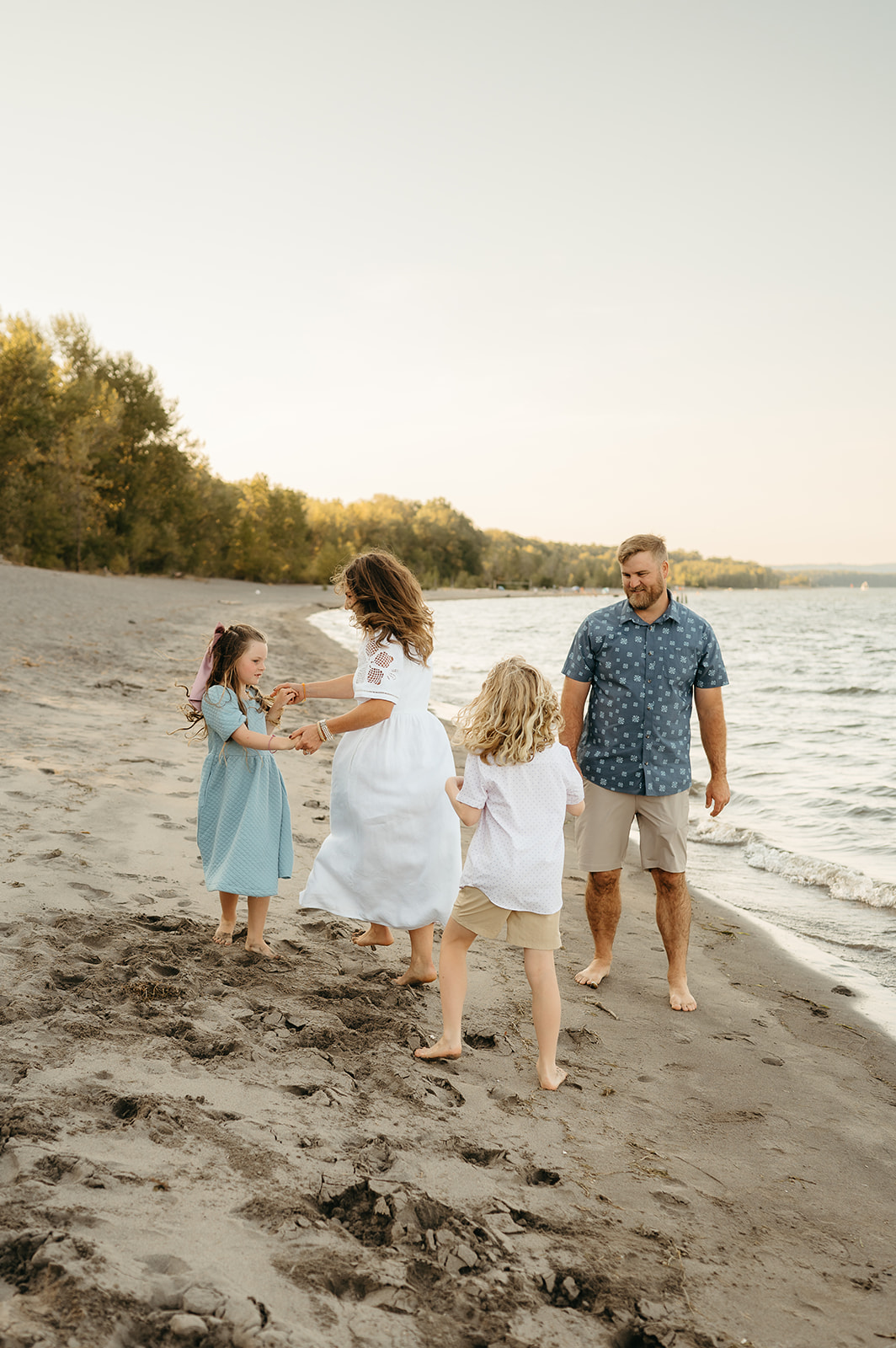 Parents walk down a beach landscape with their children, surrounded by golden fields. A timeless and candid family photography session capturing movement and joy.