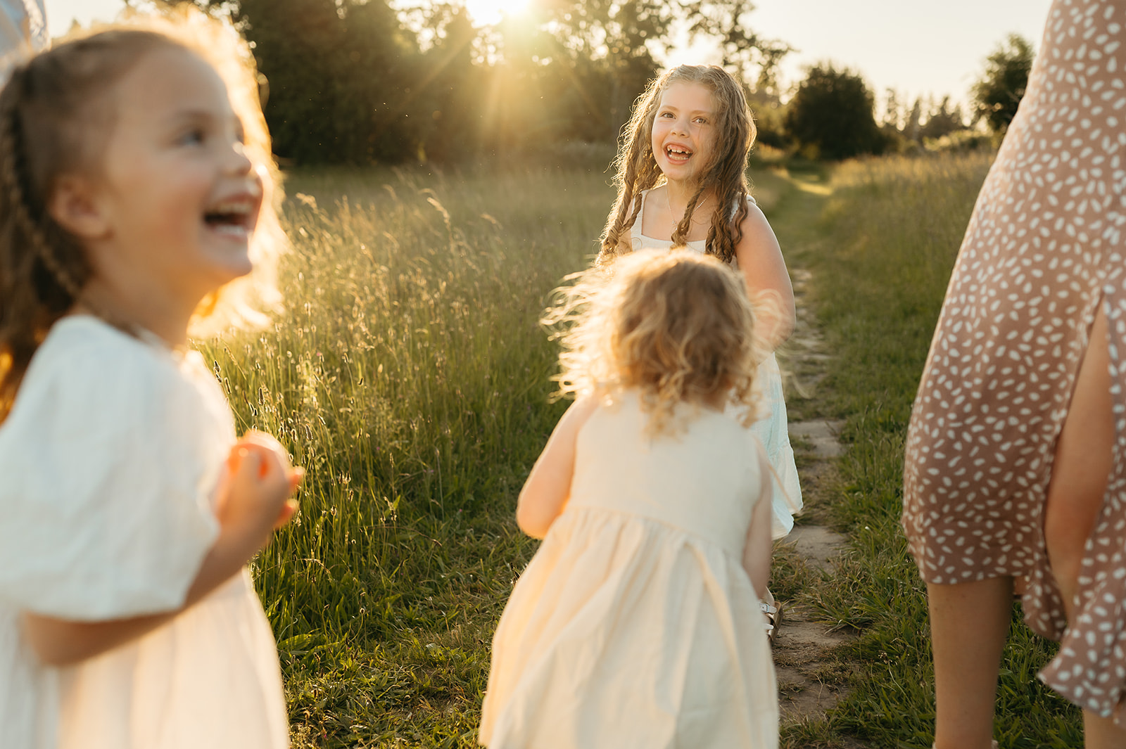 Children laughing together during a golden hour family photo session in Portland with soft sunlight and tall summer grass