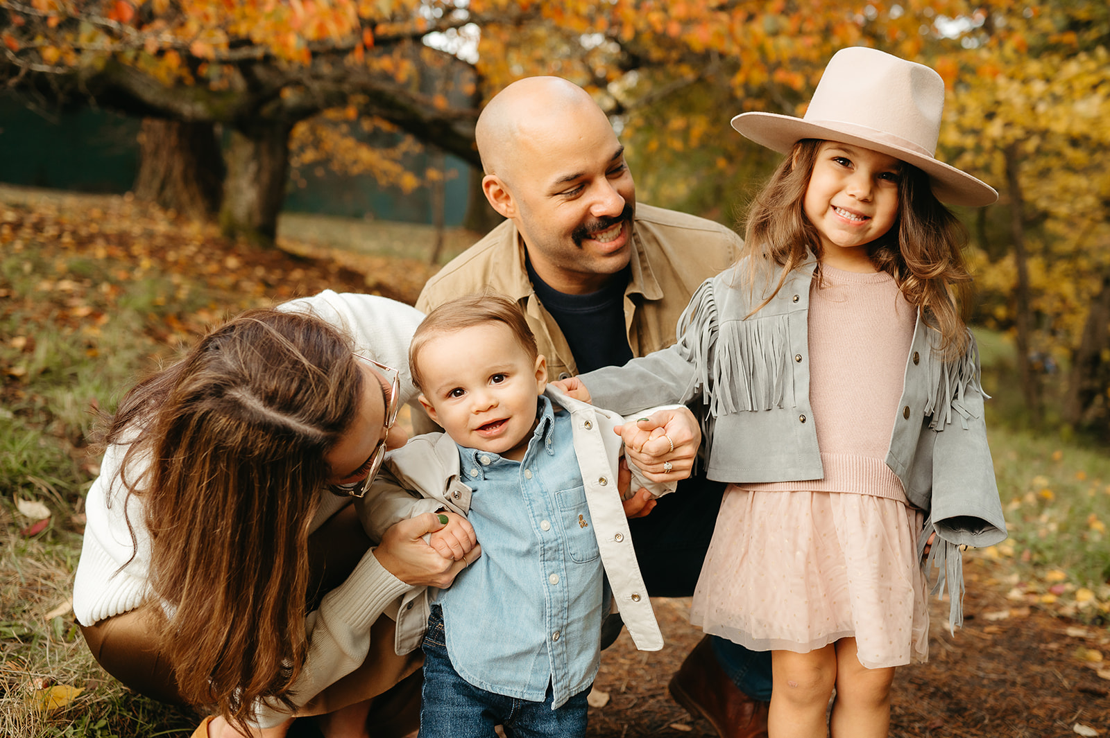family of four snuggling among fall leaves