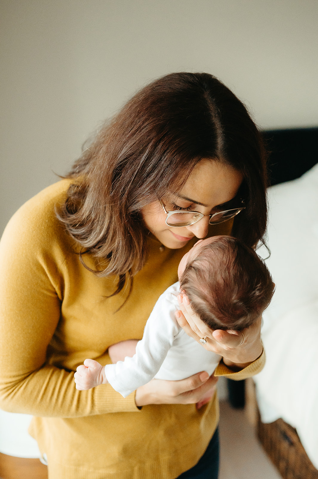 mother holding newborn baby, kissing their forehead