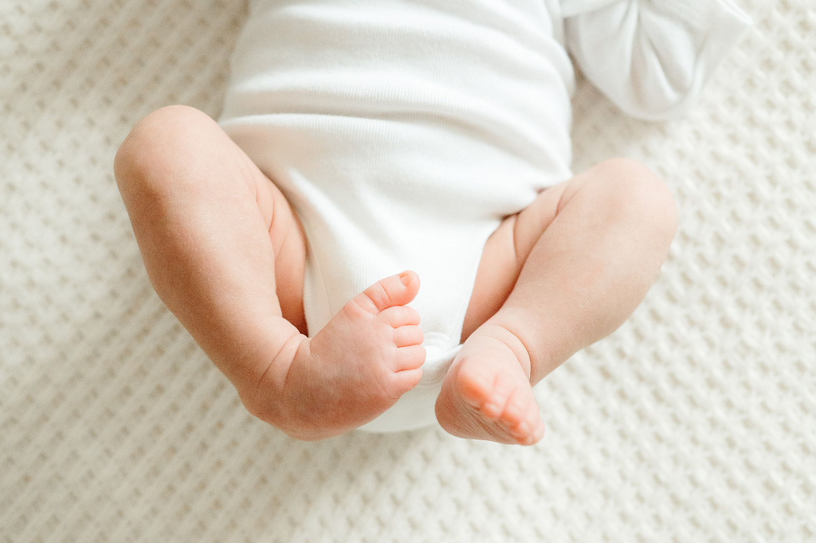 Close-up of newborn baby feet on cream blanket — detail photo from Portland in-home newborn session.