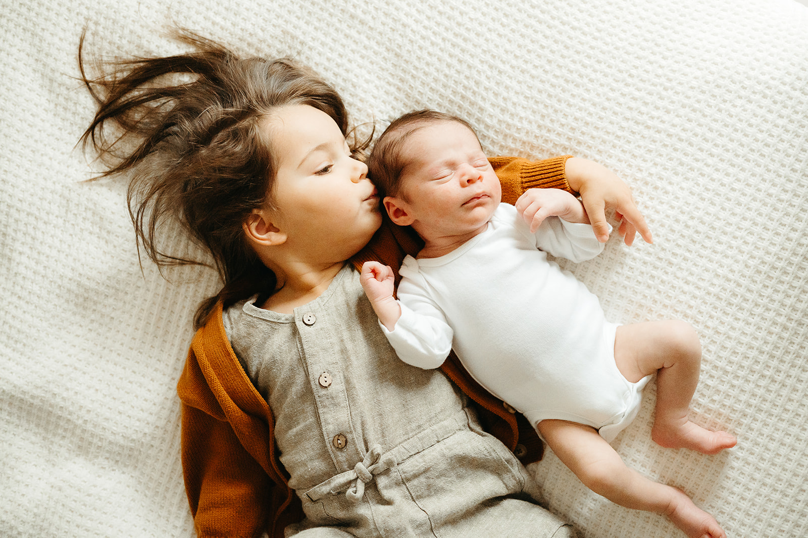 Newborn sleeping peacefully in white onesie during in-home Portland newborn session, photographed with natural light.