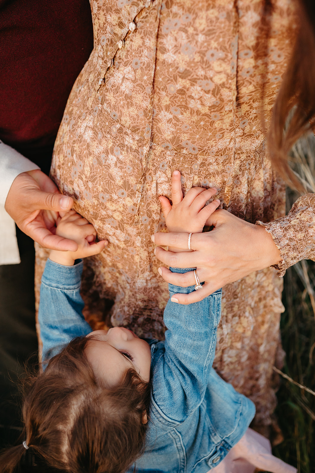 Toddler’s hands on mom’s baby bump during Portland maternity session — candid, connection-focused moment.